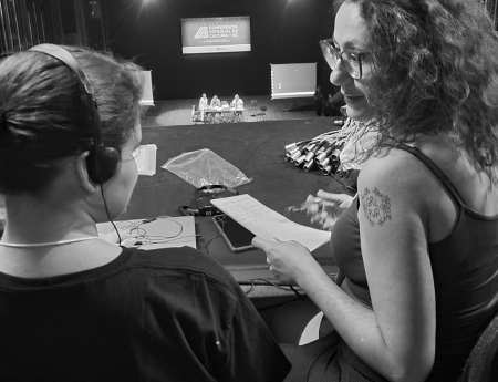 Foto em preto e branco de duas mulheres conversando, uma audiodescritora e uma consultora em audiodescrição.